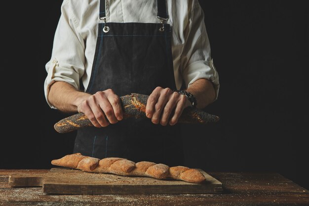 Mani che rompono e separano le baguette organiche fresche