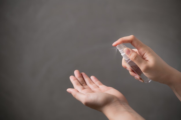 Mani che spruzzano disinfettante per mani con alcool per disinfezione igiene e protezione.