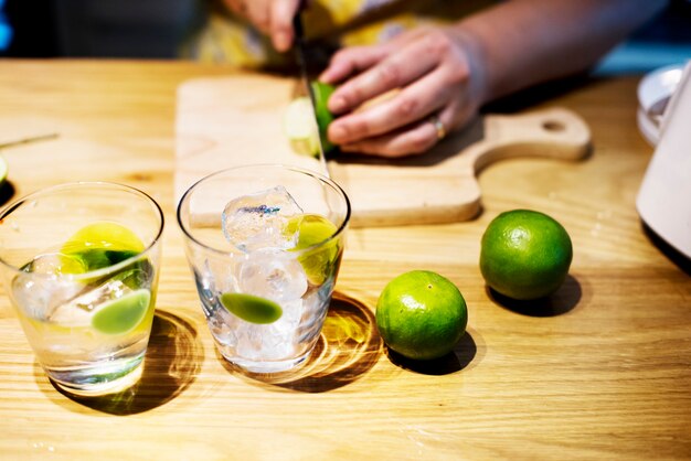 Mani che tagliano la calce preparando il mojito