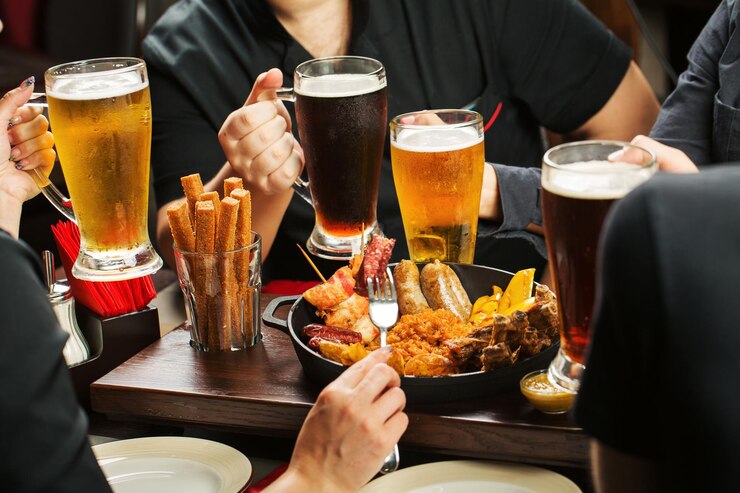 Mani che tengono bicchieri di birra che bevono insieme nel pub