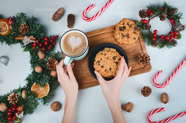 Mani che tengono caffè e biscotto d'avena