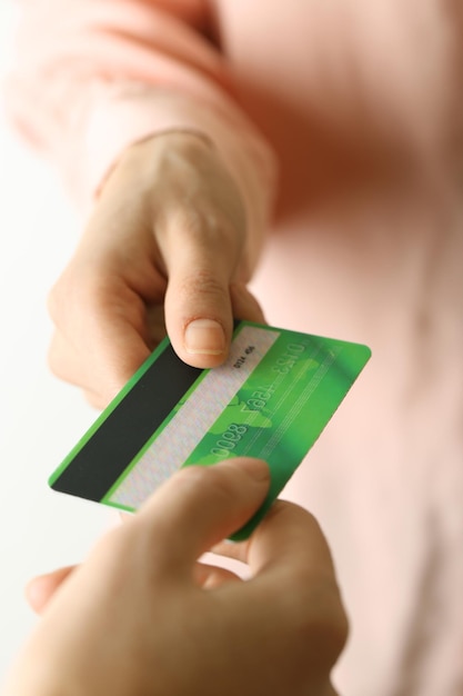 Mani che tengono carta di credito verde su sfondo bianco