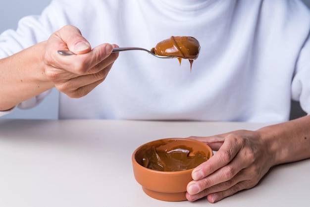 Mani che tengono cucchiaio con dulce de leche