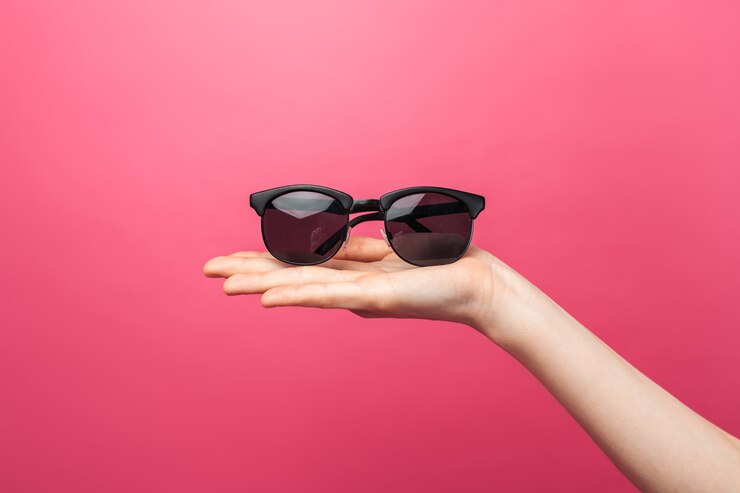Mani che tengono i vetri, sulla parete isolata rosa, vetri di pubblicità, estate
