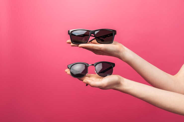 Mani che tengono i vetri, sulla parete isolata rosa, vetri di pubblicità