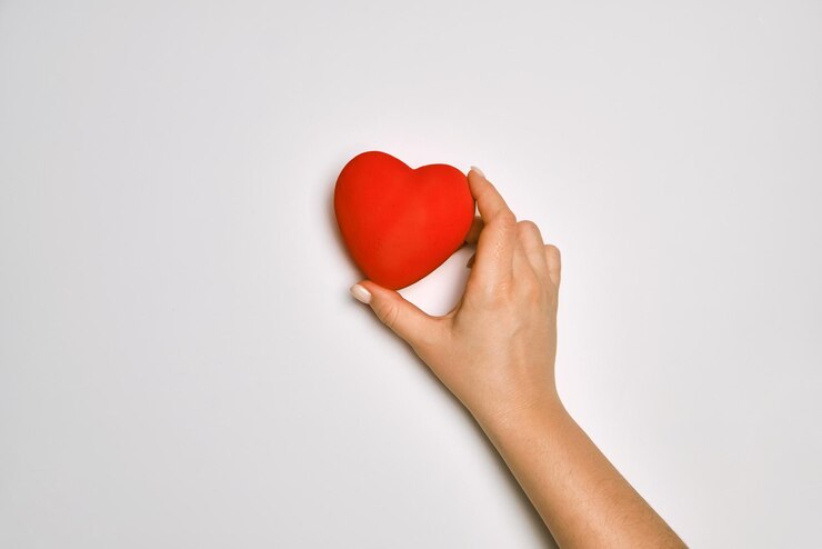 Mani che tengono il concetto di preghiera per la donazione di organi d'amore per l'assistenza sanitaria del cuore rosso