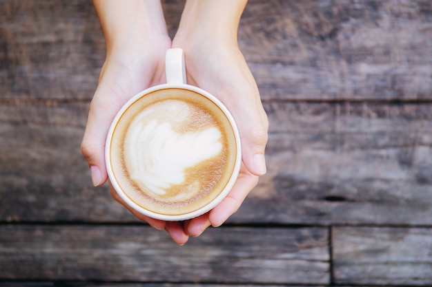 Mani che tengono il poliziotto del caffè su legno.