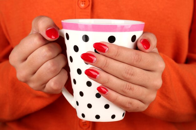 Mani che tengono il primo piano della tazza di bevanda calda