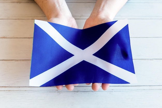 Mani che tengono la bandiera della Scozia
