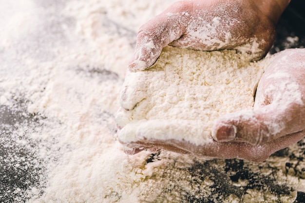 Mani che tengono la farina di grano bianco