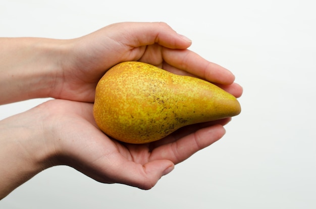 mani che tengono pera gialla su sfondo bianco