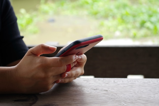 mani che tengono smartphone sul tavolo di legno