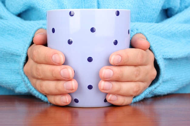 Mani che tengono tazza di bevanda calda, primo piano