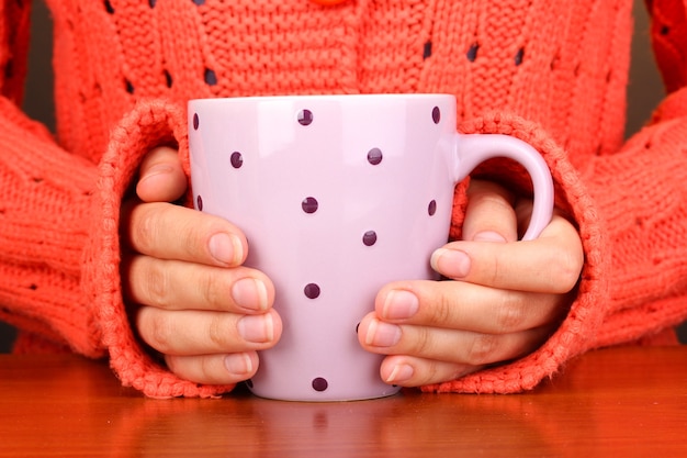 Mani che tengono tazza di bevanda calda, primo piano