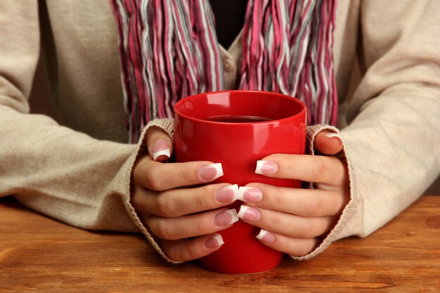 Mani che tengono tazza di bevanda calda, primo piano