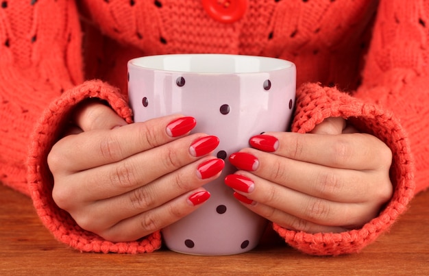 Mani che tengono tazza di bevanda calda, primo piano