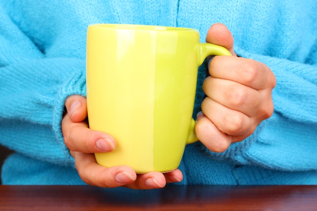 Mani che tengono tazza di bevanda calda, primo piano