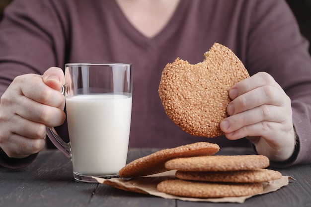 Mani che tengono tazza di caffè e biscotti sulla tavola nera