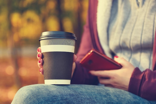 Mani che tengono tazza di caffè e telefono