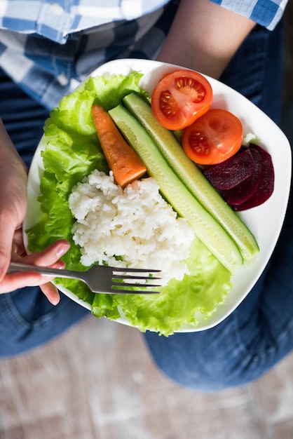 Mani che tengono un piatto con verdure e riso