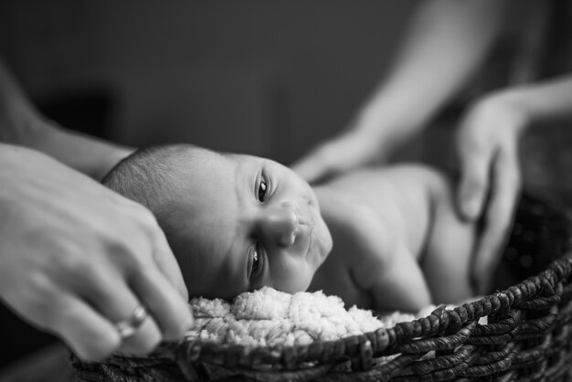 Mani che tengono un piccolo bambino appena nato sveglio sdraiato a pancia in giù