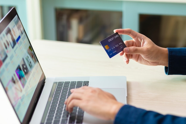 Mani che utilizzano un computer portatile e una carta di credito per il pagamento online