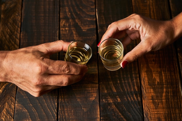 Mani con bicchierini tostatura. Concetto di alcolismo e dipendenza.