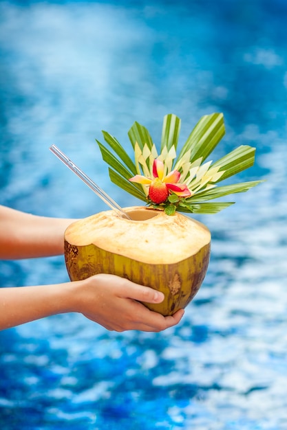 Mani con cocco sullo sfondo della piscina