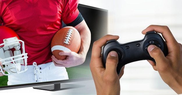 Mani con controller di gioco davanti allo schermo della TV con il portiere che allunga la palla