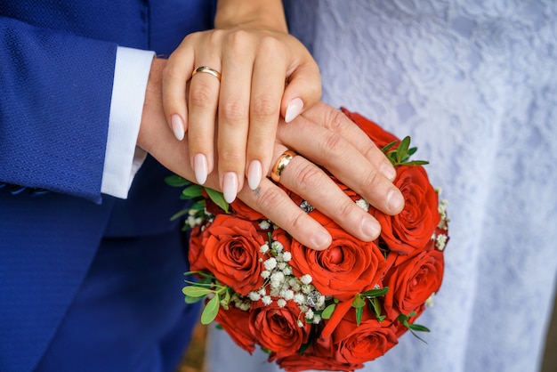 Mani con fedi nuziali sul bouquet della sposa