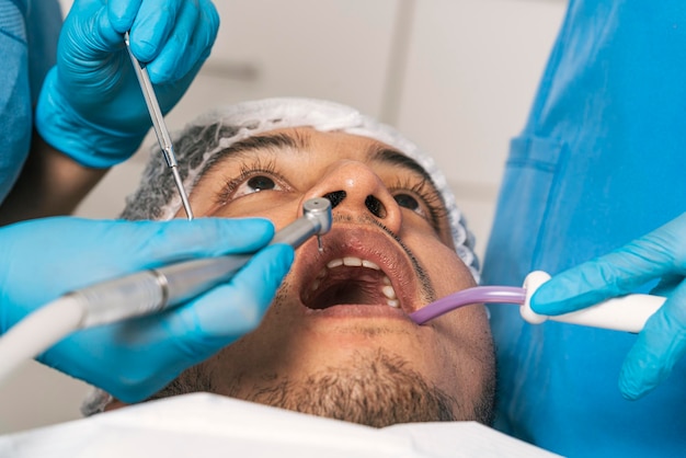 Mani con guanti che utilizzano strumenti dentali che lavorano nella bocca di un paziente