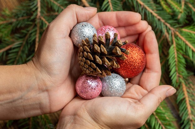 Mani con palle di Natale e pigna