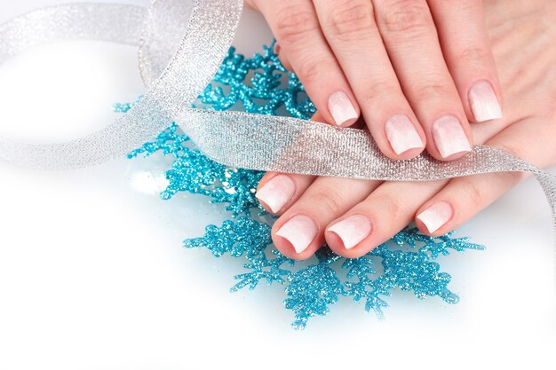 Mani con un bellissimo design invernale, fiocchi di neve e nastro solated sulla superficie bianca