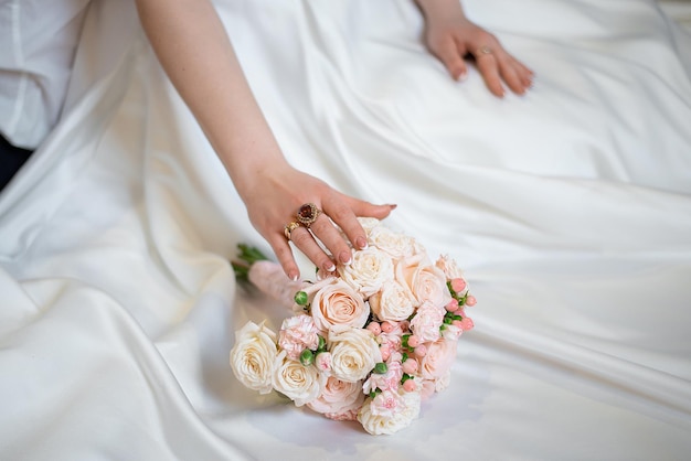 Mani con un bouquet da sposa dell'abito della sposa e dello sposo e holidayxA