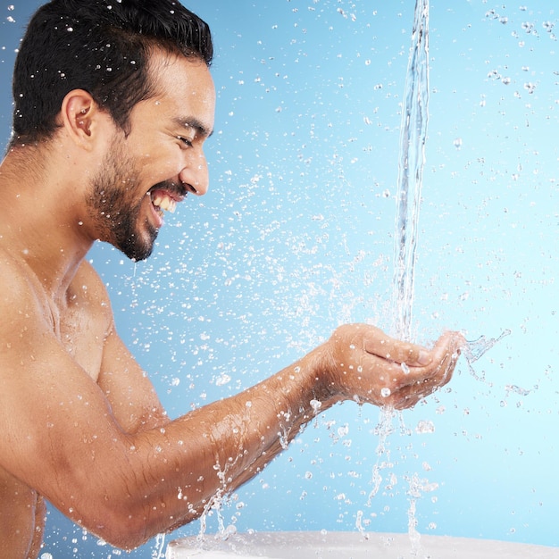 Mani d'acqua o uomo sotto la doccia in studio per la pulizia del corpo per il benessere o la cura della pelle con un sorriso felice Spruzzi d'acqua mock up o lavaggio rilassato del modello per la cura personale con spazio di marketing o mockup