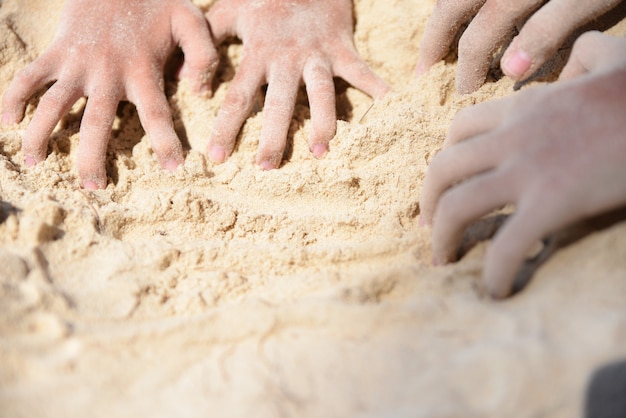 Mani dei bambini che giocano a sabbia sulla spiaggia. Concetto di giorno d&#39;estate. Bambini felici in vacanza al mare.