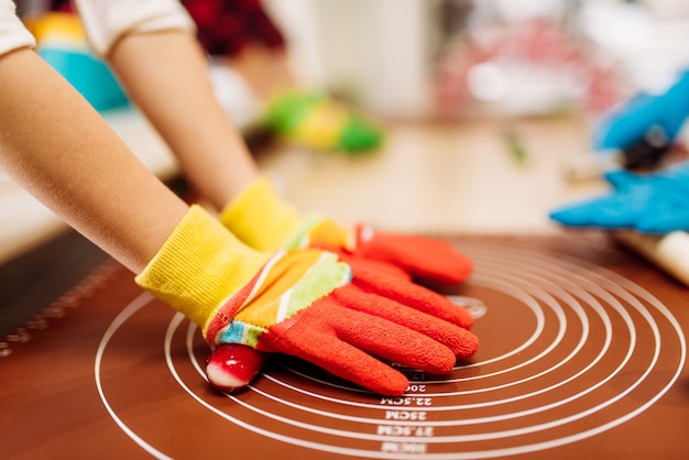 Mani dei bambini in guanti, caramello in pasticceria. Divertimento in vacanza nel negozio di caramelle. Processo di preparazione del lecca-lecca