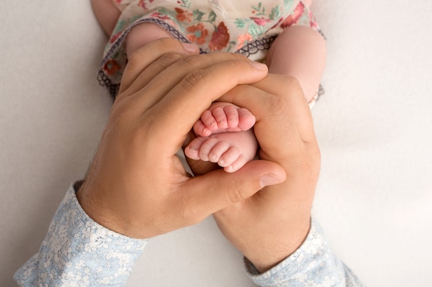 Mani dei genitori. Le gambe, i piedi del neonato nelle mani di mamma e papà. Foto di alta qualità