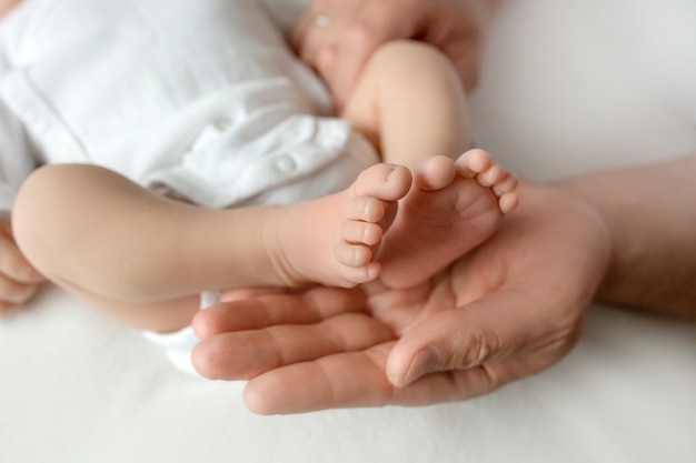 Mani dei genitori. Le gambe, i piedi del neonato nelle mani di mamma e papà. Foto di alta qualità