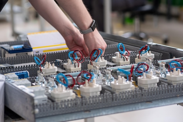 Mani dei lavoratori che assemblano stazioni di ricarica per veicoli elettrici in officina