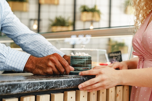 Mani del barista che serve una tazza di cioccolata calda decorata con marshmellows sul bancone