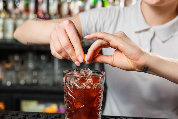 Mani del barista della donna che preparano un cocktail dell'alcool al bar