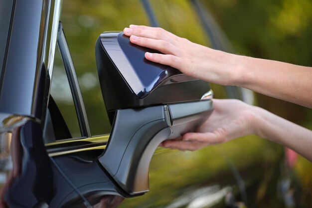 Mani del conducente che regolano lo specchio laterale di un'auto