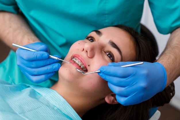Mani del dentista lavorando su giovane paziente adolescente con apparecchi ortodontici.