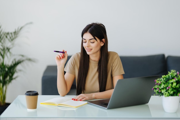 Mani del freelancer della giovane donna con la scrittura della penna sul taccuino a casa o in ufficio