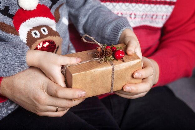 Mani del genitore e del bambino che tengono una confezione regalo di Natale.