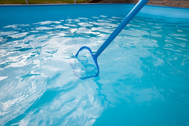 Mani del giovane che puliscono la piscina al netto della polvere