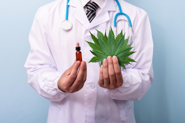 Mani del medico che tengono foglie di cannabis e olio Medico che prescrive l'estratto di marijuana