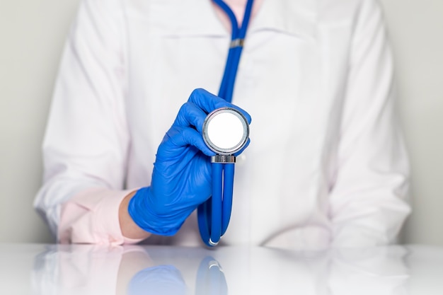 Mani del medico in guanti con lo stetoscopio, concetto di esame medico.