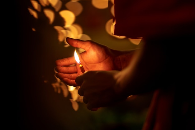 Mani del monaco buddista che tengono candela di illuminazione